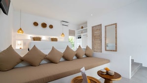A modern living room with a sofa, wooden side tables, and decorative items. - Villa Diana 3 (Tabanan)