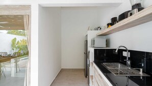 A modern kitchen with a black countertop, stainless steel sink, and a built-in oven. - Villa Diana 3 (Tabanan)