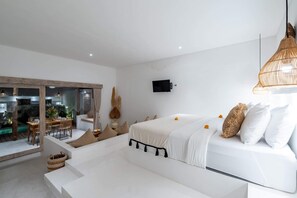 Quarto moderno com uma cama grande, área de jantar e vista através de uma parede de vidro.