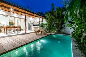 Uma casa moderna com piscina, deck de madeira e móveis para área externa.