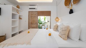 Ein modernes Hotelzimmer mit Bett, einem weißen Schrank, einer Ablage mit Dekoration und einer Hängelampe, mit Blick ins Freie.