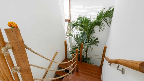 A wooden staircase with rope handrails, a potted plant, and a wooden railing. - Villa Konstelasi (Tabanan)
