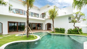 A modern two-story house with a swimming pool, large windows, and a balcony with outdoor furniture. - Villa Konstelasi (Tabanan)