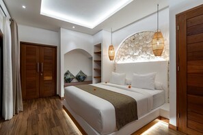 A bedroom with a bed, wooden wardrobe, and a stone wall. - Villa Naya Bali (Tabanan)