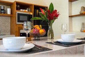 A modern kitchen with a marble countertop, a fruit bowl, a vase with flowers, and a coffee machine. - Villa Luna by Elysian (Kerobokan)