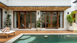 A modern house with a swimming pool, wooden deck, and large sliding glass doors. - Villa Yen by Elysian (Kerobokan)