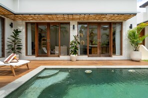 Ein modernes Haus mit Swimmingpool, Holzterrasse und großen Schiebeglastüren.