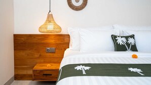 A neatly arranged bedroom with a wooden headboard, a hanging light fixture, a bed with white and green bedding, and two wall decorations. - Villa Yen by Elysian (Kerobokan)