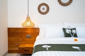 Ein ordentlich eingerichtetes Schlafzimmer mit einem Holz-Kopfteil, einer Pendelleuchte, einem Bett mit weißer und grüner Bettwäsche und zwei Wandbildern.
