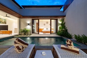 A modern hotel room with a pool, white wicker furniture, and a view of the bedroom. - Villa Segia by Elysian (Kerobokan)