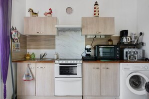 Ett kompakt kök med spis, ugn, mikrovågsugn och tvättmaskin.