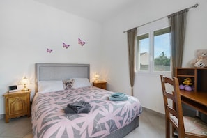 Une chambre à coucher comprenant un lit, des tables de chevet, une chaise, une fenêtre avec des rideaux et des éléments de décoration murale.
