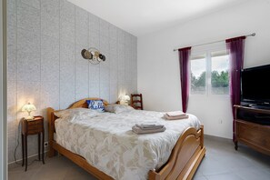 Una camera da letto con un letto, comodini, una TV e una finestra con tende.