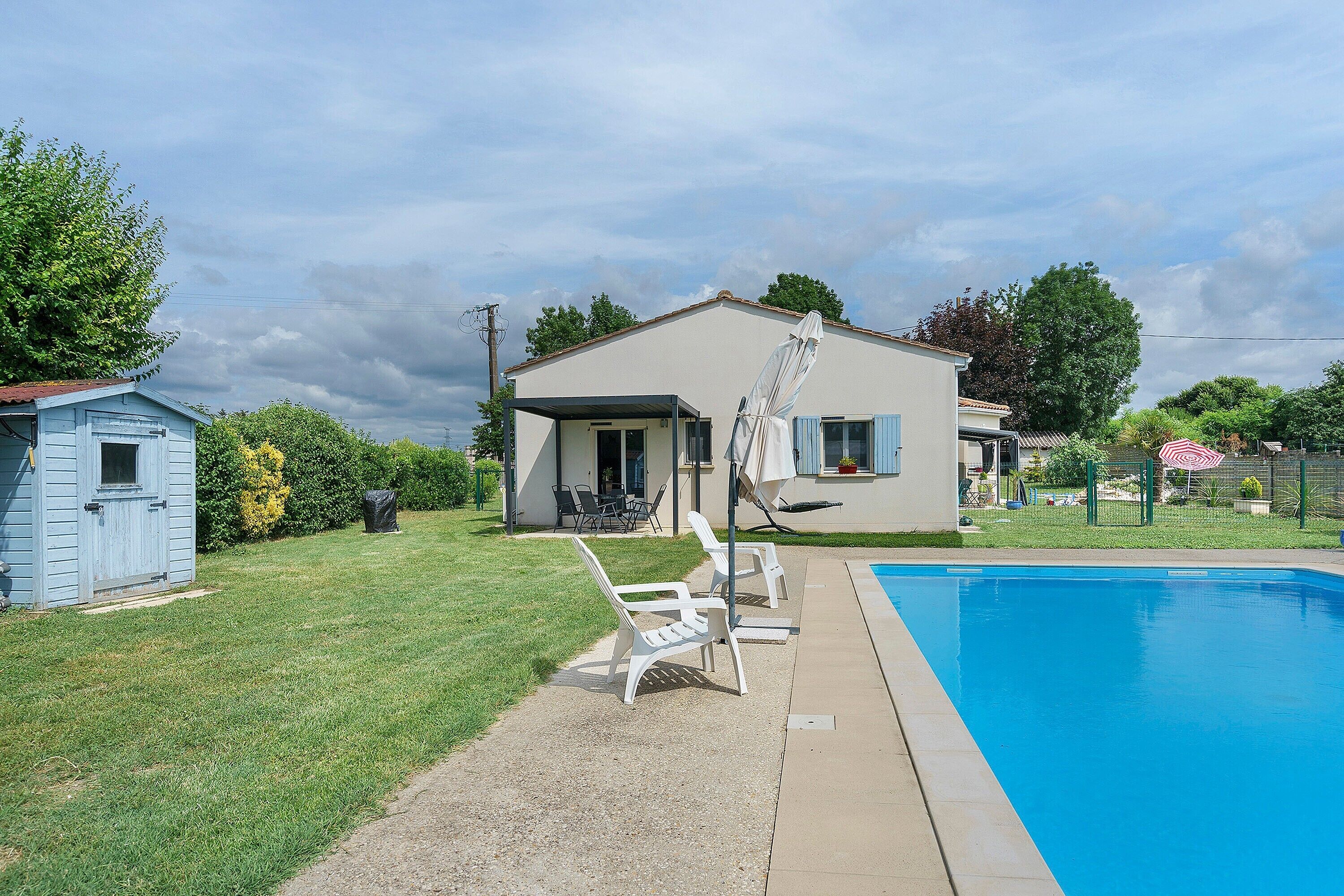 A residential area with a swimming pool, a house with a satellite dish, and a small shed.