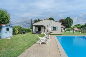 Una zona residenziale con piscina, una casa dotata di parabola e un piccolo deposito.