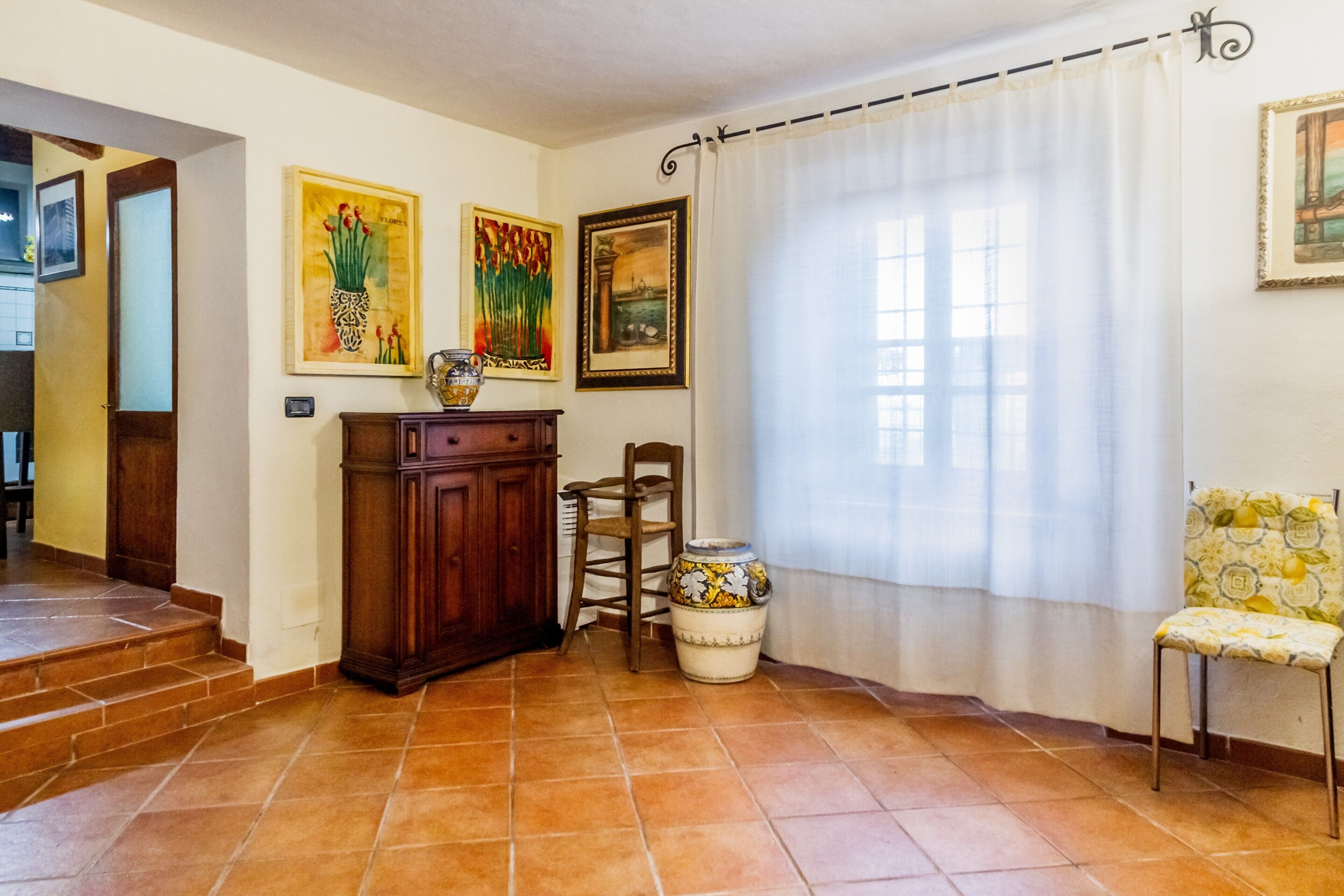 Une pièce comprenant un meuble en bois, une chaise, un vase et trois tableaux encadrés accrochés au mur.