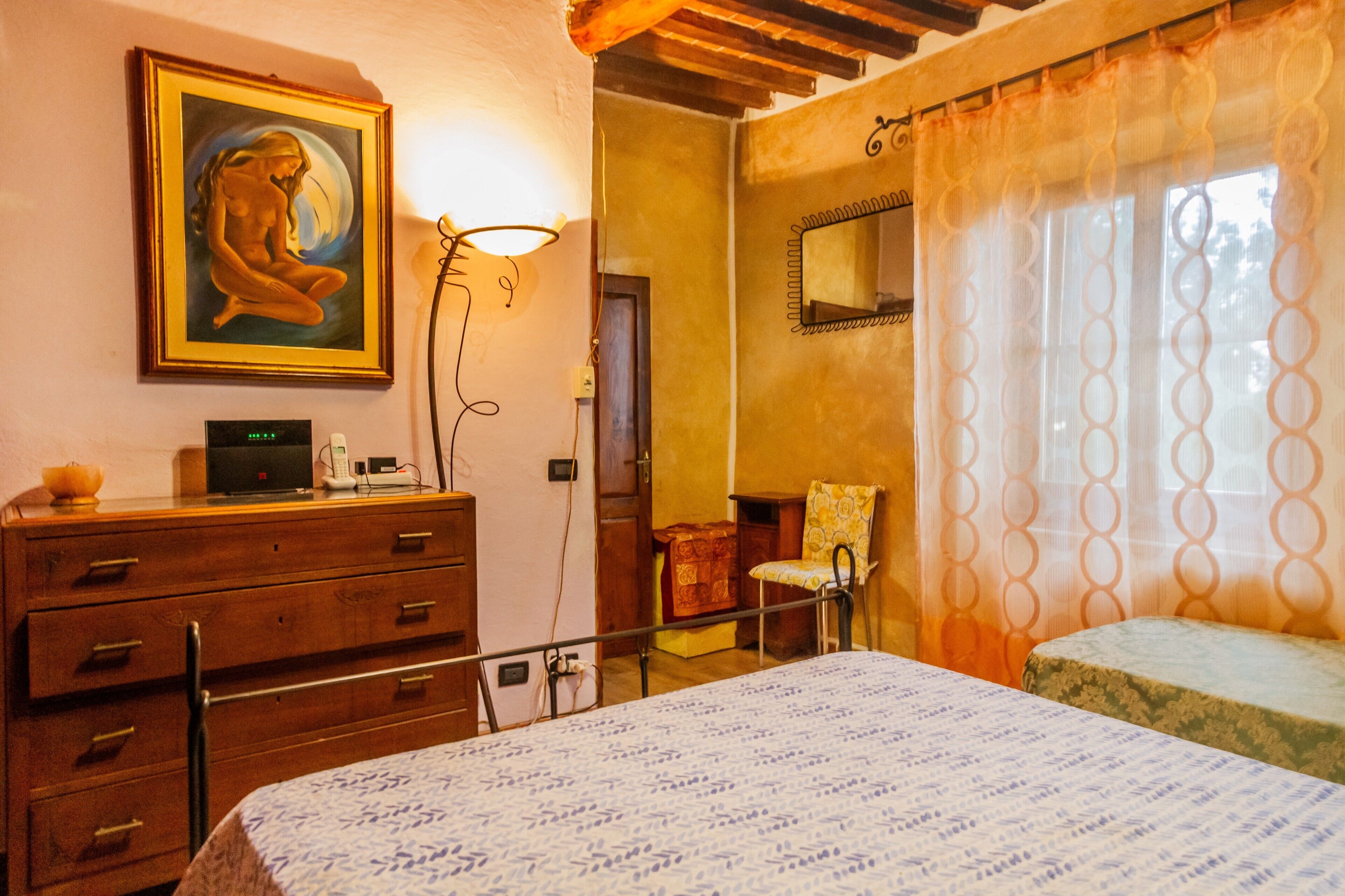 Une chambre à coucher avec un lit, une commode, une chaise, un tableau et un miroir.