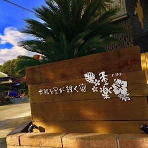 Une enseigne en bois ornée de caractères japonais et de motifs floraux, qui indique probablement un hôtel ou un complexe touristique.