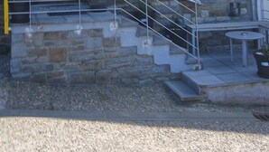 Un edificio in pietra con una scala, due finestre e una porta.