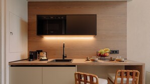 A compact kitchen with a built-in oven, a coffee maker, and a fruit bowl on the counter. - Standard Villa - Kyklio Pavilions Nafplio (Nafplio)