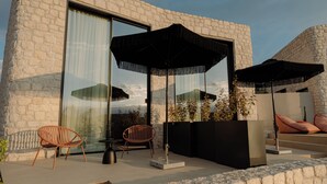 A modern outdoor seating area with two chairs, a table, and two large umbrellas. - Standard Villa - Kyklio Pavilions Nafplio (Nafplio)