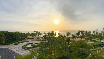 A coastal resort with a roundabout, palm trees, and a view of the sea.