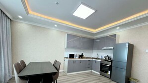 A modern kitchen with grey cabinets, a black dining table, and a built-in oven. - 30 Convenient Central 2BR Apartment (Ulaanbaatar)