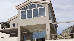 Una casa moderna de dos pisos con una escalera destacada que conduce a la entrada.