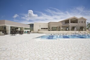 Un hotel moderno con piscina, zona de estar al aire libre y cielo despejado.