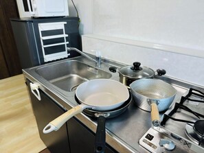 Kylskåp, mikrovågsugn, spishäll och grytor/köksredskap