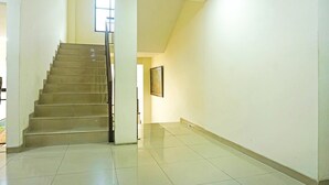 Un escalier menant à un étage supérieur, un tableau encadré accroché au mur et un sol carrelé.