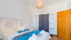 Une chambre d’hôtel comprenant un lit, une armoire, un espace douche et un luminaire suspendu.