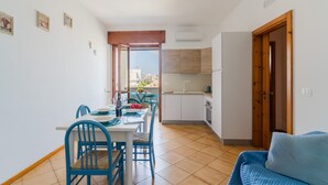 Un coin repas avec une table et des chaises, une cuisine équipée d’armoires et une porte en bois.