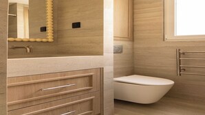 A modern bathroom with a beige vanity, a white toilet, and a mirror with a decorative frame. - Design Apartment a/c 1BR/4P - Saint-Germain (Paris)
