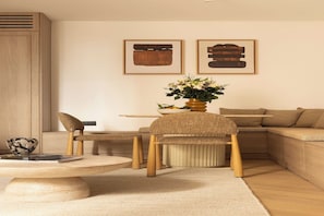 A modern living room with a round coffee table, two chairs, a sofa, and a side table. There are framed artworks on the wall and a vase with flowers on the side table. - Design Apartment a/c 1BR/4P - Saint-Germain (Paris)