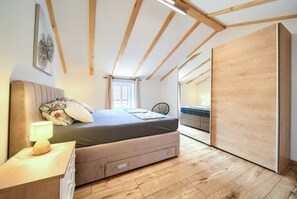 A bedroom with a bed, bedside table, lamp, and a view of another room. - Apartment Veris in the heart of the old town of Vrbnik (Vrbnik)