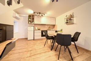 A modern kitchen with white cabinets, a dining table with chairs, and a built-in oven. - Apartment Veris in the heart of the old town of Vrbnik (Vrbnik)