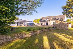 A stone house with a grassy yard, a stone wall, and a tree. - Holiday home with a garden near Men Du beach (La Trinité-sur-Mer)