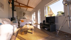 Ein geräumiges Wohnzimmer mit hoher Decke, Kamin, Fernseher und großem Fenster.
