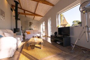A spacious living room with a high ceiling, a fireplace, a television, and a large window. - Holiday home with a garden near Men Du beach (La Trinité-sur-Mer)