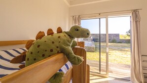 Ein Schlafzimmer mit Bett, großem Fenster und Blick ins Freie.