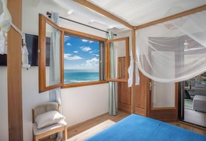 A bedroom with a large window, a bed, a chair, and a wardrobe. - Quatre Vents (Sainte-Luce)