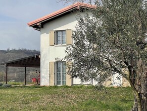 A two-story house with a covered patio, a tree in front, and a view of the countryside. - Lake View Country Glam House "SAN MARTINE" (2+2+1+3 guests) Family Villa for up to 8 guests (Lombardia)
