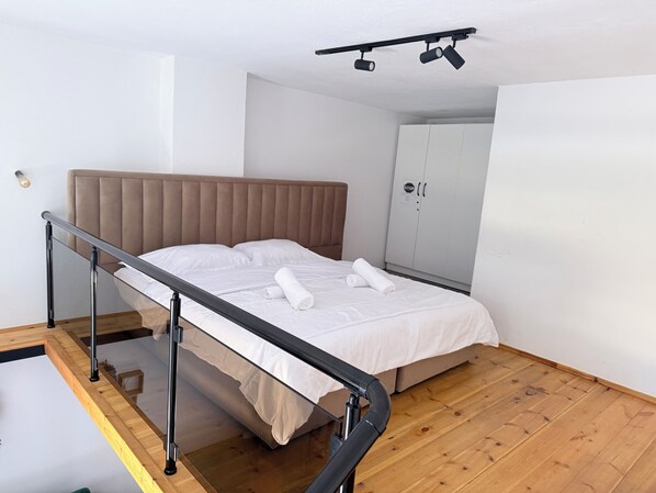 Une chambre à coucher comprenant un lit, une tête de lit, une armoire et une rambarde.