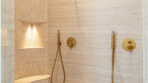 Een moderne douche met een gebogen wand, een handdouche en een douchekop aan de muur.