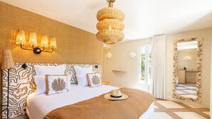 Een slaapkamer met een bed, een wandlamp, een spiegel met een bloemenversiering en uitzicht op de omgeving.