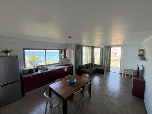 A compact living space with a kitchen, dining area, and seating area with a view of the ocean.