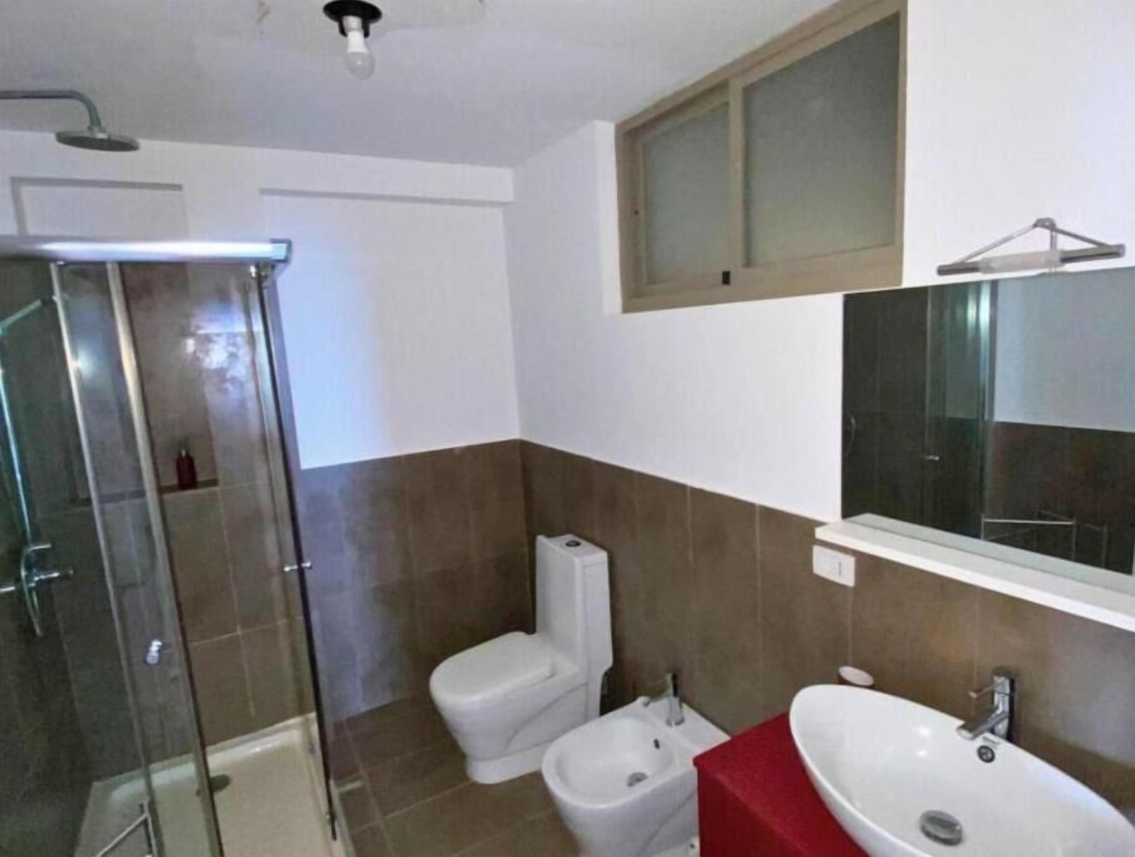 A bathroom with a shower, toilet, bidet, and sink.