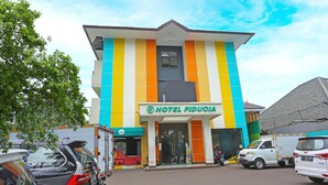 A multi-story hotel with a colorful facade, a visible entrance, and parked vehicles in front. - Luxury Twin Stay with Free WiFi and Parking (Jakarta)
