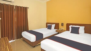 A hotel room with two beds, a wooden desk, a telephone, and a wall-mounted air conditioner. - Luxury Twin Stay with Free WiFi and Parking (Jakarta)